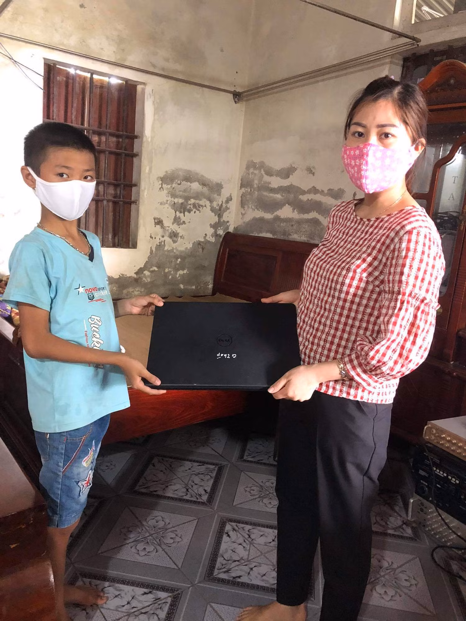 Cô Ngô Thị Báu, cán bộ văn phòng trao máy tính hỗ trợ học sinh học trực tuyến (Ảnh nhà trường cung cấp).
