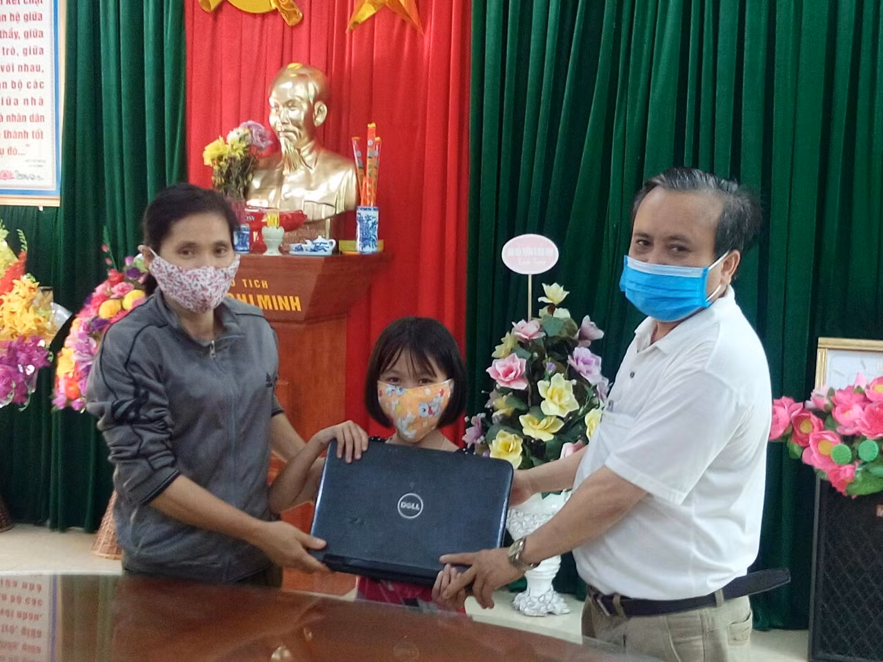 Thầy Trần Trọng Ninh, Hiệu trưởng nhà trường đang trao máy tính cho học sinh về học trực tuyến (Ảnh nhà trường cung cấp)