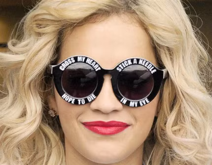 Đầu tiên phải kể đến ngôi sao nhạc Pop - Rita Ora bởi chiếc kính tròn in sologan trắng vô cùng độc đáo. Nữ ca sĩ đã kiêu hãnh đeo chiếc kính thể hiện “cái tôi” có đôi chút cuồng nhiệt và nổi loạn khi tham dự một Show truyền hình của BBC.