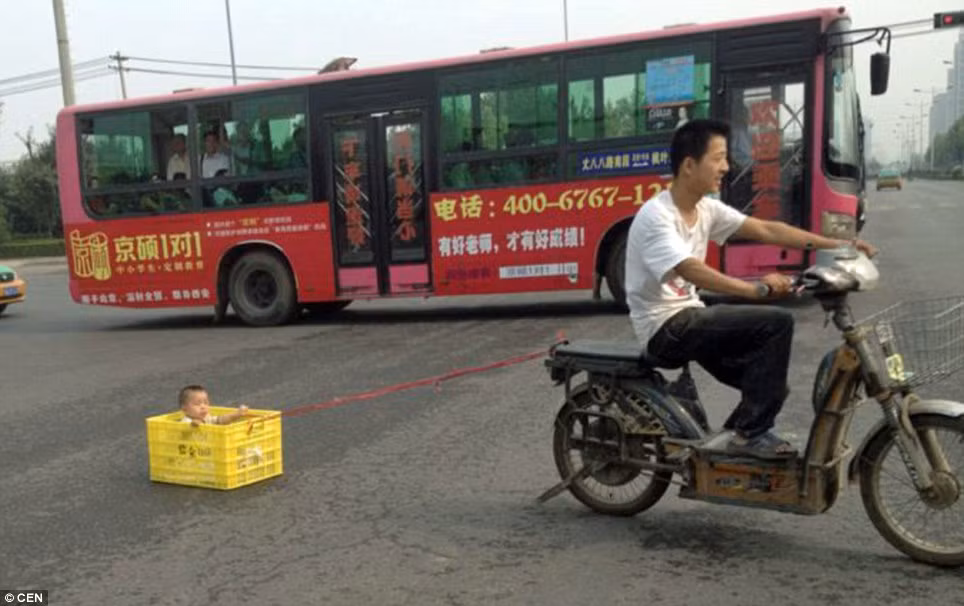 Đứa bé bị đặt trong thùng đựng đồ uống và gắn với xe máy bằng một sợi dây. Đứa bé bị đặt trong thùng đựng đồ uống và gắn với xe máy bằng một sợi dây.