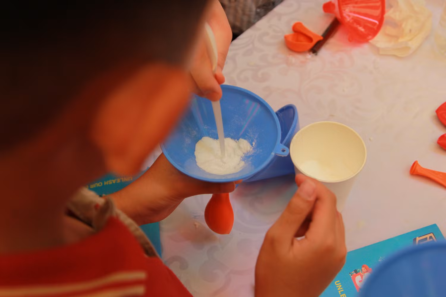 Các em học sinh còn được trực tiếp tham gia các hoạt động có tính chất khoa học, sáng tạo. Ví như trong hình là học sinh đang cho bột baking soda vào bên trong quả bóng. (Ảnh: NP) Các em học sinh còn được trực tiếp tham gia các hoạt động có tính chất khoa học, sáng tạo. Ví như trong hình là học sinh đang cho bột baking soda vào bên trong quả bóng. (Ảnh: NP)