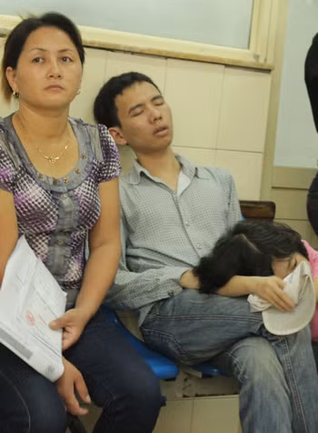 Đi sớm từ quê ra khám cho con, ông bố trẻ mệt mỏi tranh thủ chợp mắt trong lúc đợi trước cửa phòng khám. Xem thêm: Những loại quả cực tốt cho sức khỏe / Cách phòng bệnh cho bé.