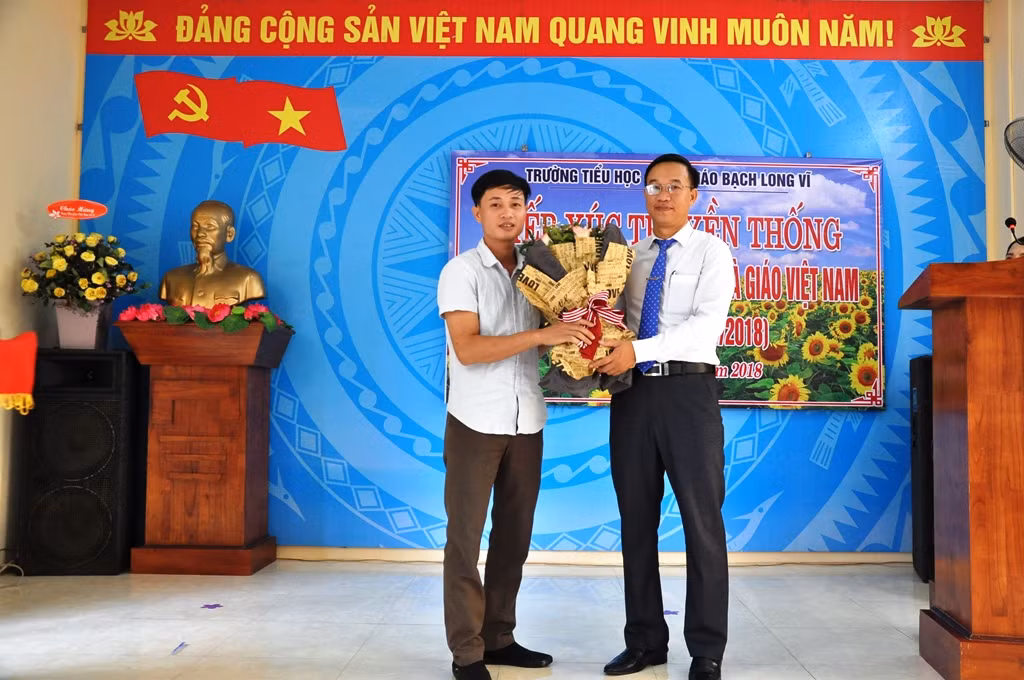 Đại diện cha mẹ học sinh tặng hoa chúc mừng các thầy cô giáo nhân ngày Hiến chương các nhà giáo. (Ảnh: BLV)