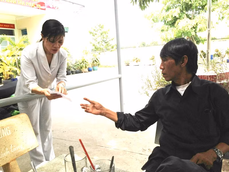 Ông Lê Đình Phú đang nhận lá đơn viết tay của bà Phạm Thị Bình, tố cáo chính vợ ông, người gây ra vụ đánh ghen kinh hoàng, chuẩn bị chạy đi đánh máy giúp.Ảnh: Dương Cầm