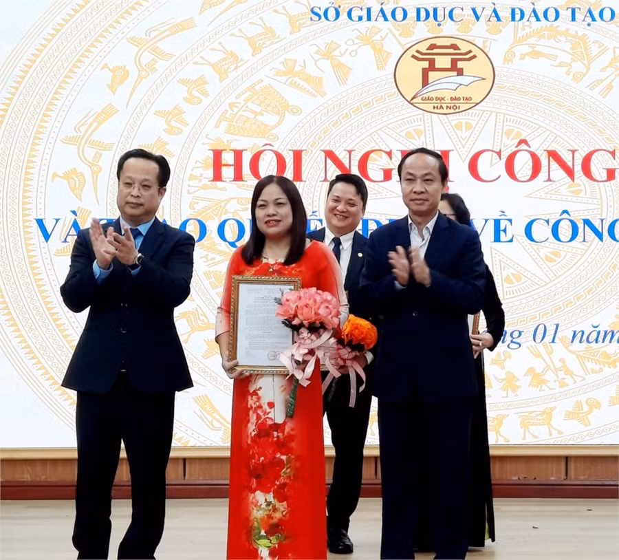 Giám đốc Sở Giáo dục và Đào tạo Trần Thế Cương cùng Phó Giám đốc Sở Giáo dục và Đào tạo Nguyễn Quang Tuấn trao quyết định và tặng hoa đồng chí Hà Thị Hằng. (Ảnh: Sở Giáo dục và Đào tạo Hà Nội).