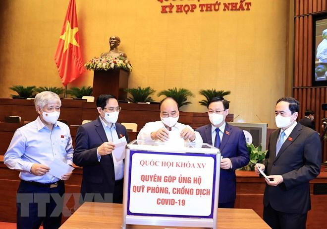 Chủ tịch nước Nguyễn Xuân Phúc, Thủ tướng Phạm Minh Chính, Chủ tịch Quốc hội Vương Đình Huệ và các đại biểu Quốc hội quyên góp ủng hộ Quỹ phòng chống dịch Covid-19. (Ảnh: Thống Nhất/TTXVN)