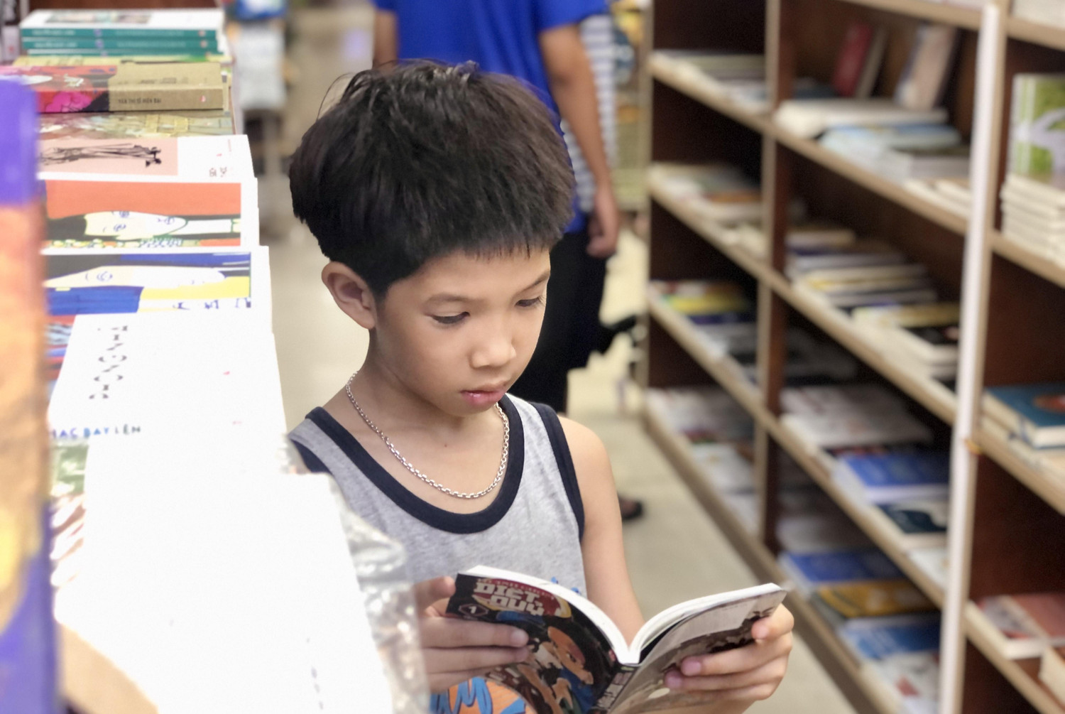 Một em nhỏ tranh thủ đứng đọc truyện ở một góc nhà sách.
