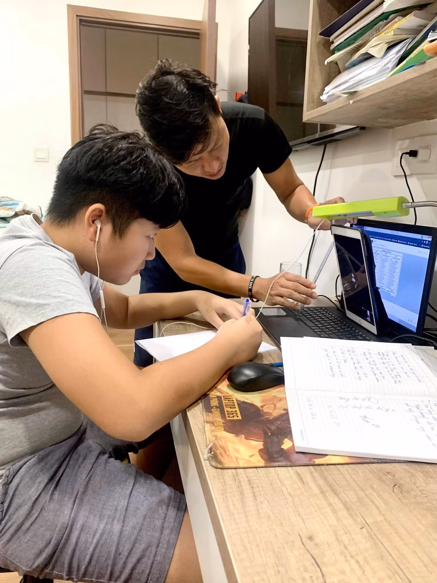 Phụ huynh hỗ trợ chỉnh cam trong giờ thi trực tuyến của con. Ảnh: Văn Hiền