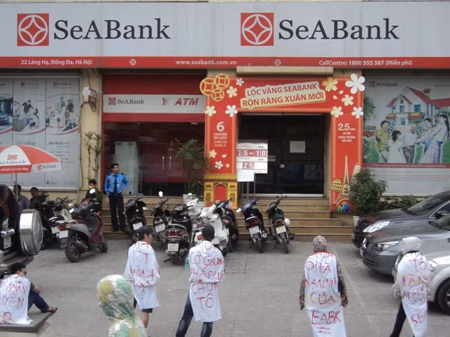 Một số người dân đeo băng rôn quanh mình trước SeaBank Láng Hạ (Ảnh: Quang Tuệ) Một số người dân đeo băng rôn quanh mình trước SeaBank Láng Hạ (Ảnh: Quang Tuệ)