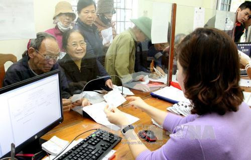 Cán bộ Bảo hiểm Xã hội Việt Nam giải đáp cho khách hàng. Ảnh: TTXVN