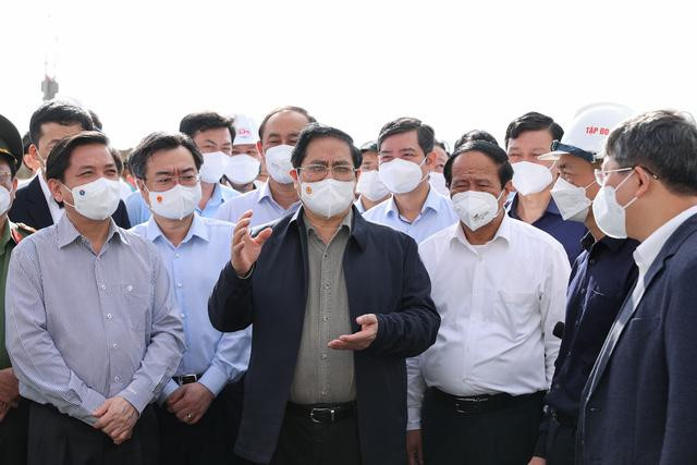 Thủ tướng Phạm Minh Chính nghe báo cáo tình hình triển khai thi công và giải quyết các đề xuất của nhà đầu tư, nhà thầu ngay trên công trường. Ảnh: VGP/Nhật Bắc