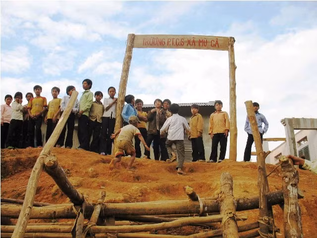 Cổng lên trường thì dốc hơn đỉnh núi, không có đường mòn lên, phải trèo núi. Cổng chỉ là mấy khúc gỗ ghép thành hình như cổng thành thời... Tam Quốc
