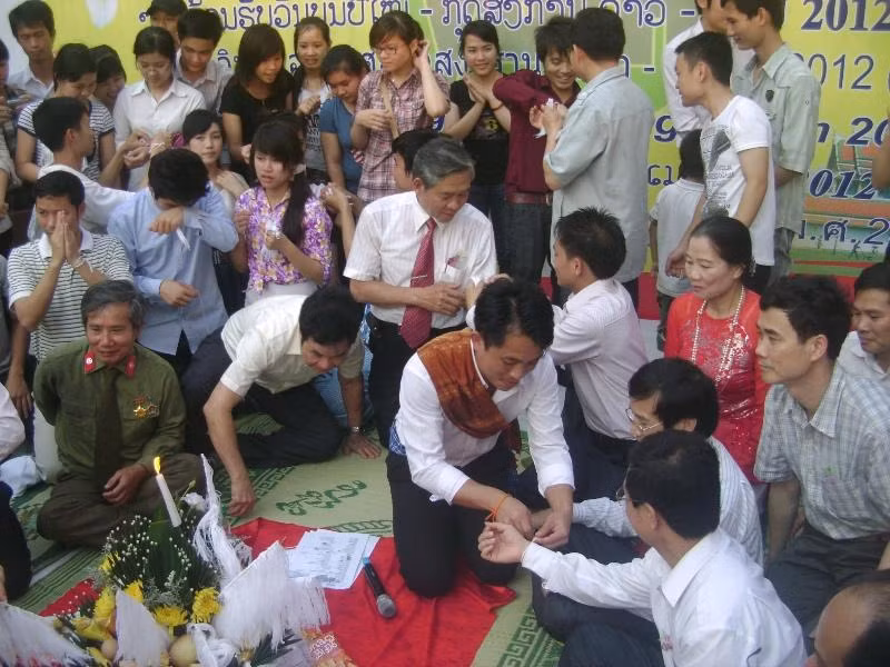 Những lưu học sinh Lào và Thái Lan đang cột chỉ chúc phúc cho các đại biểu khách mời và những người tham gia buổi lễ
