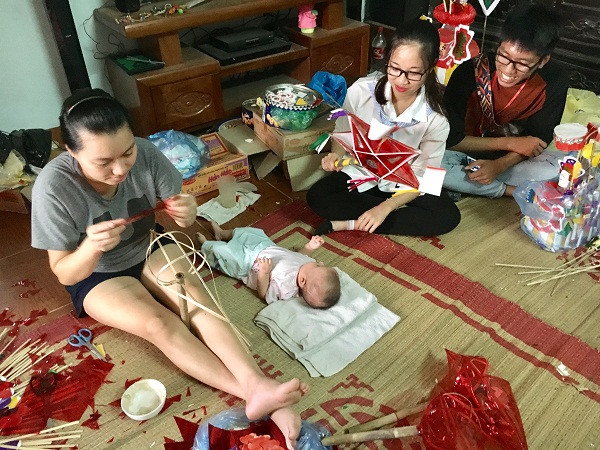 Chị Loan (trái), con gái thứ ba cùa bà Tuyến cho con gái 3 tháng tuổi đến nhà bố mẹ đẻ chơi và hỗ trợ ông bà làm đồ Trung thu. (Ảnh: Hồ Thu)