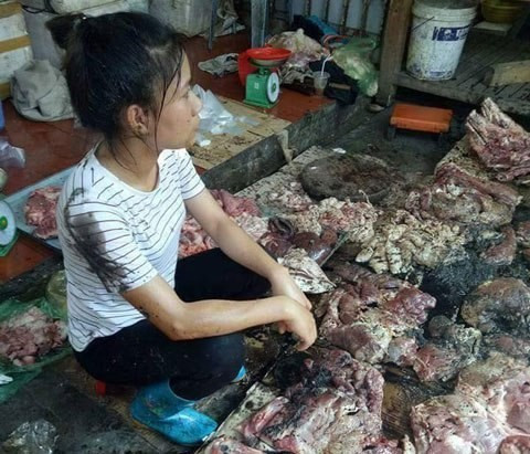 Chị Đỗ Thị Xuyến với số thịt lợn bị bọn bất lương hắt dầu luyn tại chợ. (Ảnh: vietnamnet.vn)