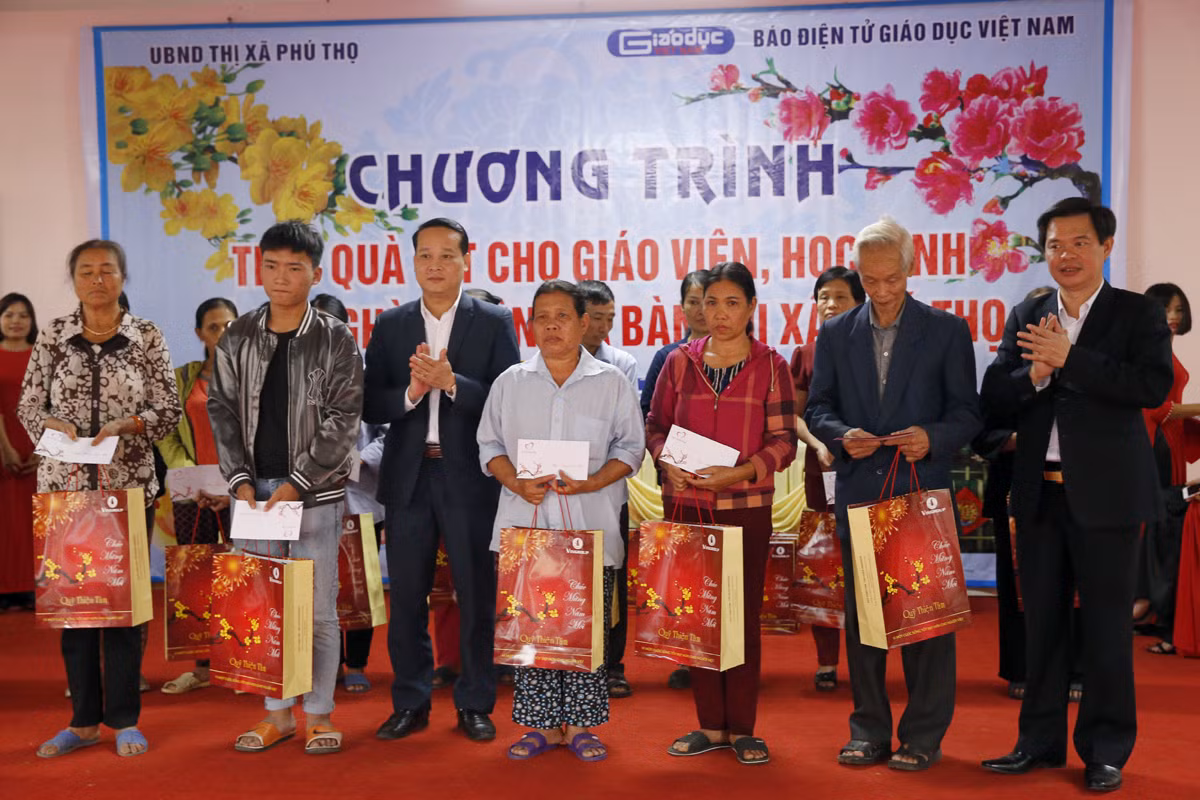 Ông Nguyễn Công Huân - phó Chủ tịch Ủy ban nhân dân thị xã Phú Thọ và Tiến sĩ Trịnh Thế Truyền - Giám đốc Sở Giáo dục và Đào tạo tỉnh Phú Thọ, đang trao quà cho các hộ nghèo. Ảnh: Tùng Dương.