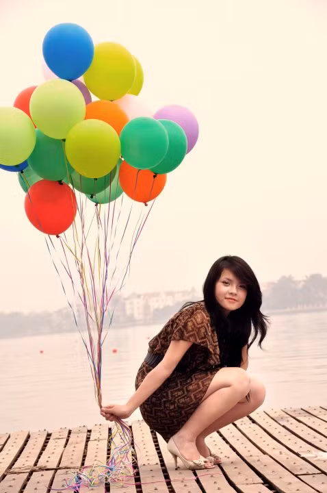 Từ góc máy này, nhờ sắc bóng bay tươi tắn, nhờ màu hoàng hôn ngả bóng mận đào, Thu Trang có được khoảnh khắc đẹp, vừa đủ cuốn hút người đối diện. Giá như mái tóc thay vì buông xõa được vấn cao, hoặc tết bím, chắc chắn sẽ tạo cho cô nàng diện mạo xì tin hơn, trẻ trung hơn.