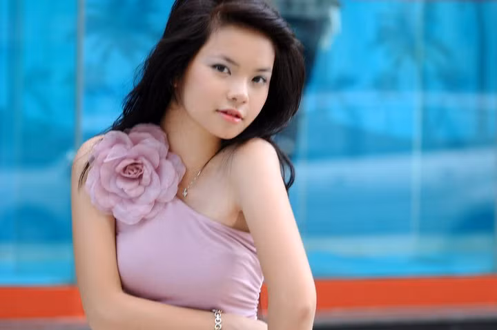 Chiếc đầm tím rất hợp với Thu Trang. Bông hoa tết nằm ngoan xinh trên bờ vai thon tượng trưng cho vẻ đẹp đang độ rực rỡ của thiếu nữ, màu tím nhẹ nhàng tượng trưng nét tính cách bí ẩn, áo vắt chéo vai tượng trưng cho xu hướng thời trang hiện đại.