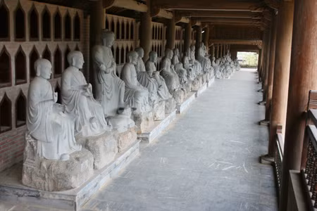 Hành lang 500 vị La Hán dài nhất (chùa Bái Đính, Ninh Bình) Từ tam quan chùa Bái Đính (Ninh Bình) đi vào là hai dãy hành lang La Hán, một dãy có chiều dài khoảng 1.700m (Tính cả hai dãy là 3.400 m ôm toàn bộ khu chùa) gồm 250 gian. Mỗi gian có kích thước 4,5m x 4,5m. Hai dãy hành lang La Hán này khởi công từ năm 2005 xây dựng bằng 10.000m 3 gỗ, thực hiện bởi sự chạm trổ, lắp ghép bởi 100 nghệ nhân và 700 người thợ. Ảnh: Internet.
