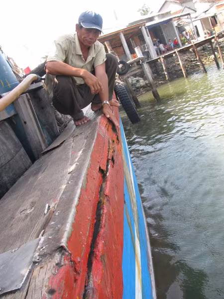 Ngư dân Trần Văn Quang bên chiếc tàu QNG 90917 bị tàu Trung Quốc đâm nứt toác.
