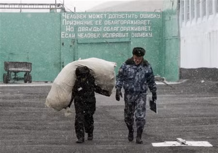 Một cảnh vệ của nhà tù Siberian, thành phố Krasnoyarsk, Nga cùng một nữ tù nhân đang vác bao tải lương thực tới nhà giam.
