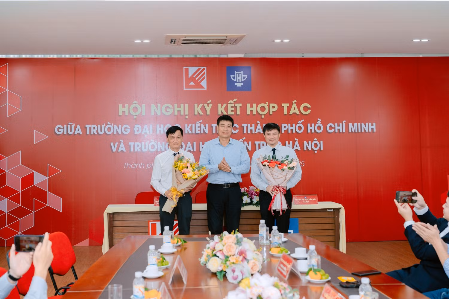 Thứ trưởng Bộ Xây dựng Phạm Minh Hà tặng hoa chúc mừng sự hợp tác giữa hai trường Đại học Kiến trúc. Ảnh: NTCC.