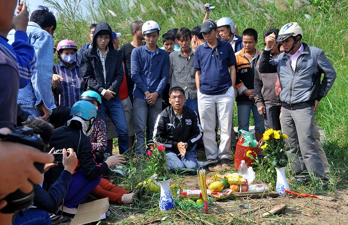 Gia đình và anh Huy quỳ lậy trước bàn làm lễ trên bờ đê sông Hồng.