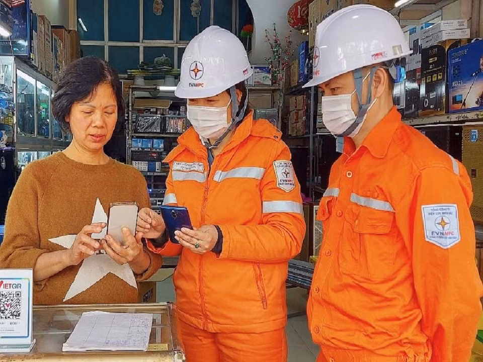 Nhân viên của EVNNPC hướng dẫn khách hàng thanh toán hóa đơn điện qua điện thoại di động Nhân viên của EVNNPC hướng dẫn khách hàng thanh toán hóa đơn điện qua điện thoại di động