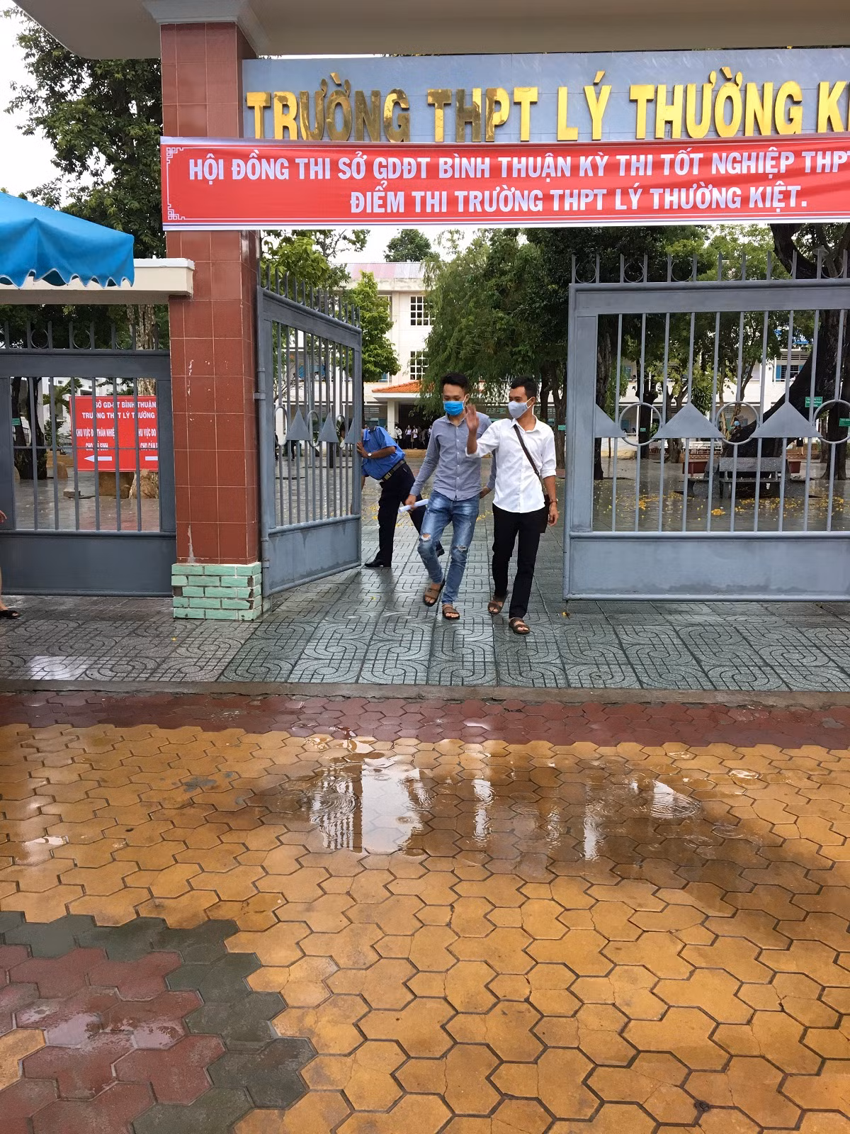 Hai học sinh đầu tiên rời phòng thi giơ tay vẫy chào đội tình nguyện (Ảnh Phan Tuyết)