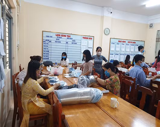 Giáo viên chủ nhiệm phân loại khẩu trang, nón chống giọt bắn cho học sinh trước khi vào lớp (ảnh: P.L) Giáo viên chủ nhiệm phân loại khẩu trang, nón chống giọt bắn cho học sinh trước khi vào lớp (ảnh: P.L)