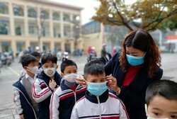 Giáo viên Trường tiểu học Chu Văn An hướng dẫn học sinh đeo khẩu trang đúng cách (Ảnh: Lã Tiến)