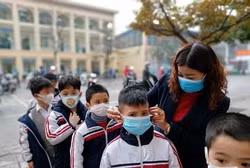 Giáo viên Trường tiểu học Chu Văn An hướng dẫn học sinh đeo khẩu trang đúng cách (Ảnh: Lã Tiến)