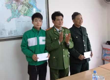 Đại tá Lê Văn Nghiêm (giữa) trao thưởng cho 2 quần chúng có thành tích trong việc đảm bảo an ninh trật tự trên địa bàn (ảnh Duy Tuyên)