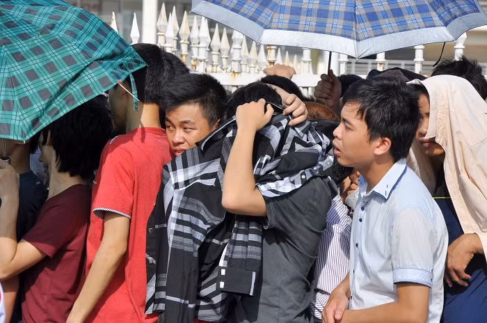 Người mua vé dùng đủ mọi cách để chống nắng trong lúc xếp hàng Người mua vé dùng đủ mọi cách để chống nắng trong lúc xếp hàng