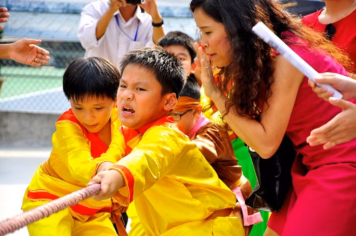Dùng hết sức để chơi trò kéo co trong sự hò reo, cổ vũ của bạn bè và cha mẹ.