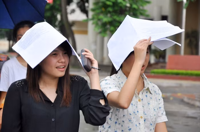 Sĩ tử kết thúc môn thi thứ 2, nhiều bạn lấy túi đựng giấy tờ để che mưa.