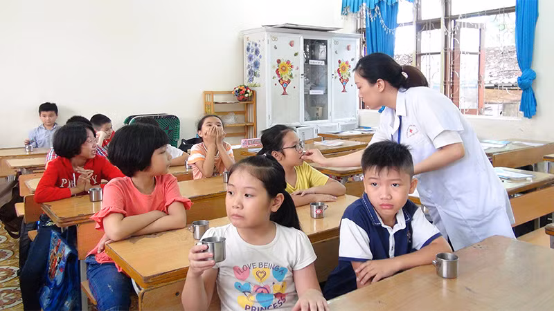 Cán bộ Y tế cho trẻ uống thuốc tẩy giun tại Trường Tiểu học Trần Hưng Đạo (thành phố Hạ Long, Quảng Ninh) - (Ảnh: Minh Khương)