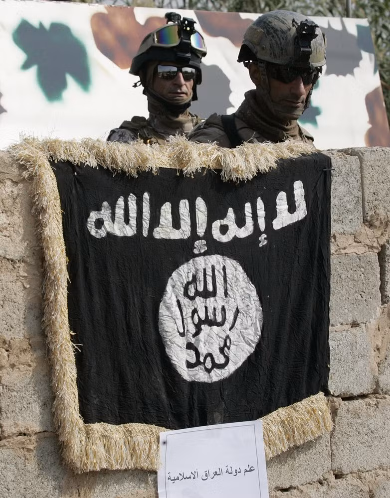 Nhà chức trách Iraq cho biết một phiến quân tình nghi là khủng bố đã bị bắt giữ và ngay sau đó một cuộc bao vây đã được tiến hành để khống chế và thu giữ kho vũ khí này. Trong ảnh là lá cờ của tổ chức khủng bố có liên quan đến Al-Qaeda được treo trên tường của ngôi nhà có vũ khí được cất giấu.