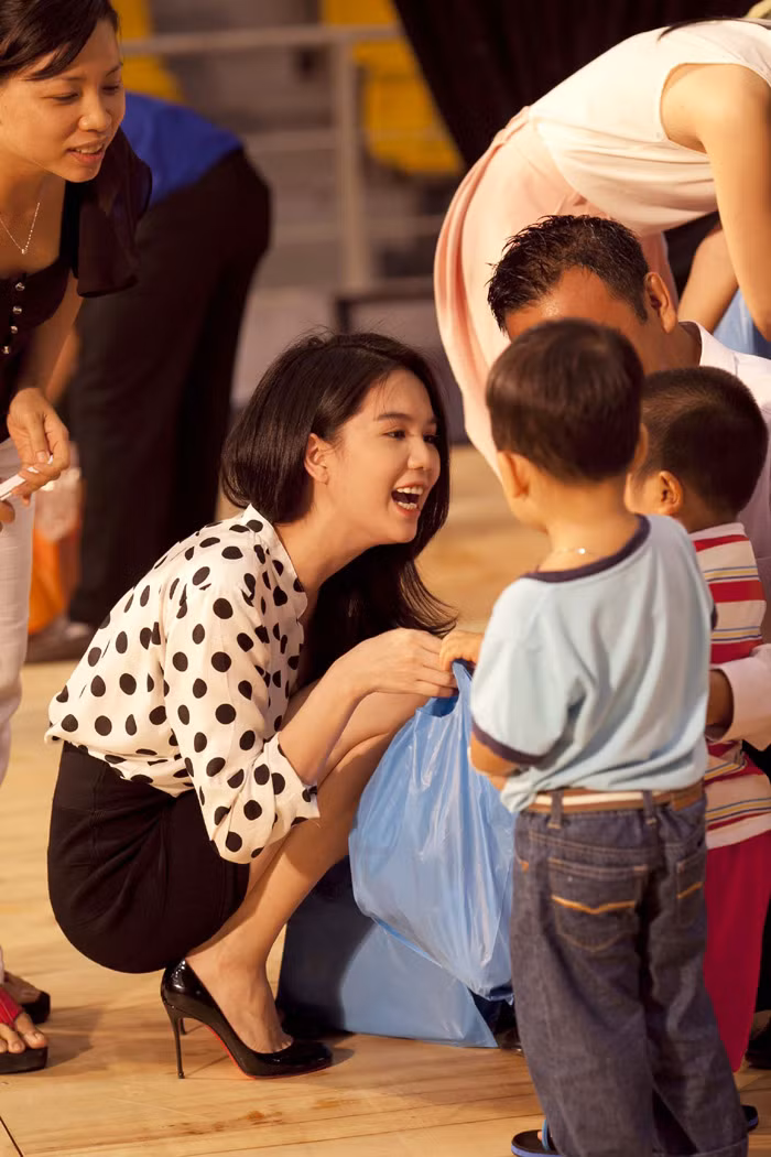 Ngọc Trinh ăn mặc giản dị và luôn nở nụ cười trên môi với các em nhỏ.