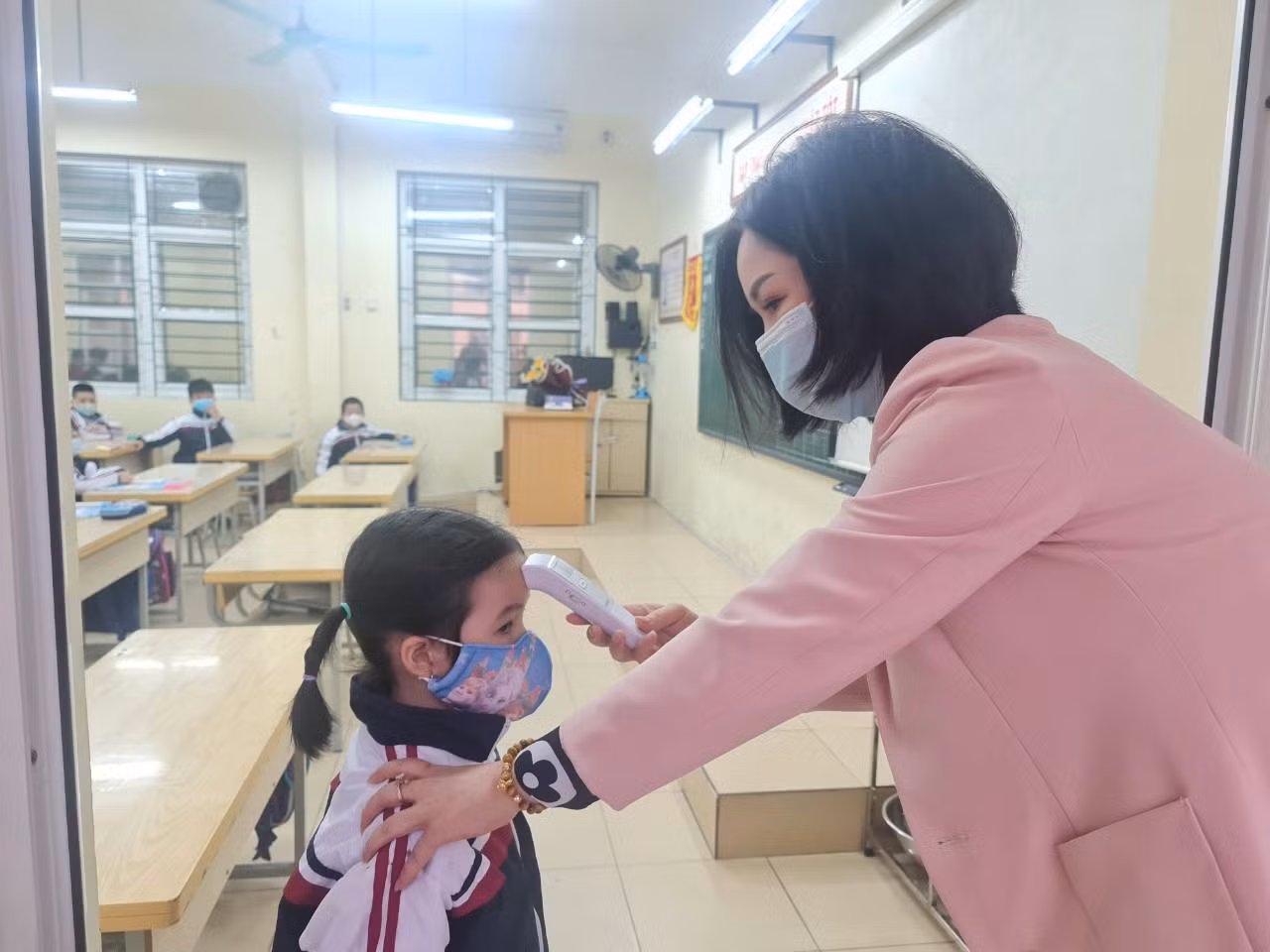 Học sinh Trường Tiểu học Chu Văn An được đo thân nhiệt trước khi vào lớp (Ảnh: Lã Tiến)