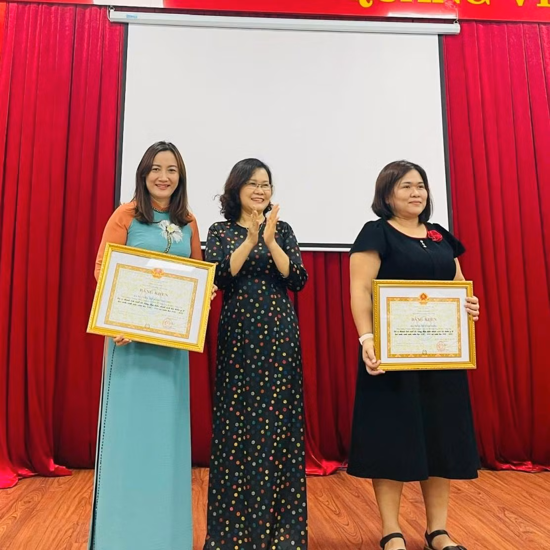 Cô Nguyễn Thị Sông Thương (bìa trái), Hiệu trưởng trường Trung học cơ sở Nguyễn An Ninh thay mặt nhà trường nhận Bằng khen
