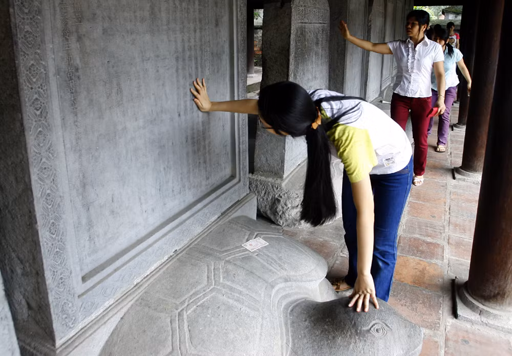 Đến các em học sinh cũng cho rằng xoa tay vào đầu rùa ở Văn Miếu là sẽ thi được điểm cao. Ảnh: Tùng Dương. Đến các em học sinh cũng cho rằng xoa tay vào đầu rùa ở Văn Miếu là sẽ thi được điểm cao. Ảnh: Tùng Dương.