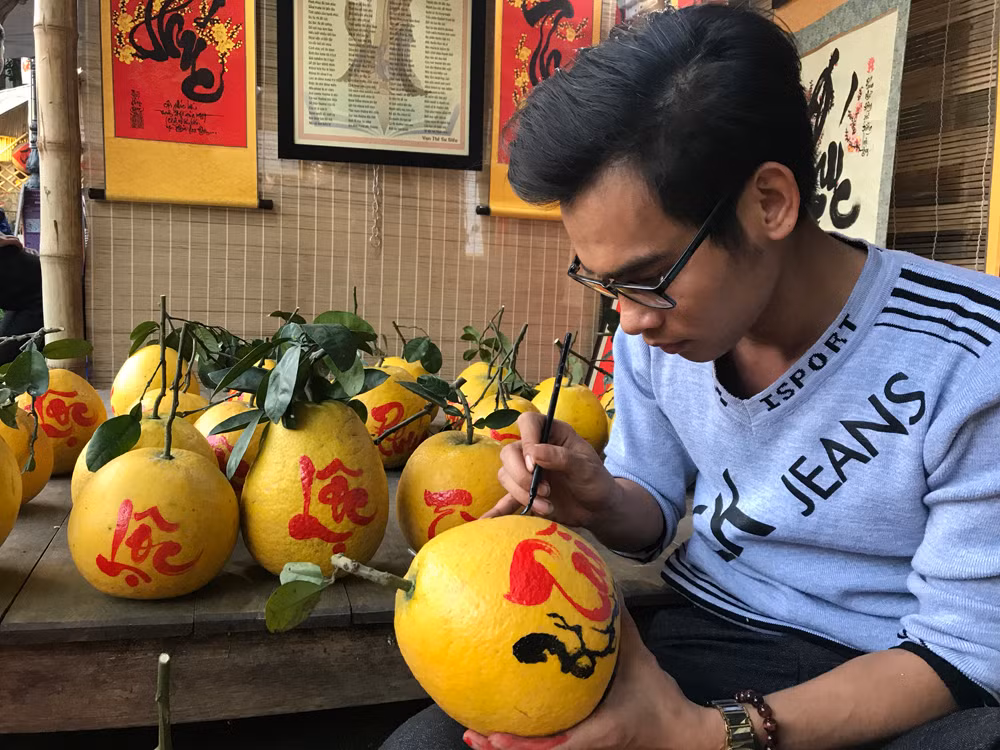 Anh Đỗ Duy Đợi, câu lạc bộ Thư pháp Unesco Việt đang viết chữ lên nhưng trái bưởi. Ảnh: Tùng Dương.