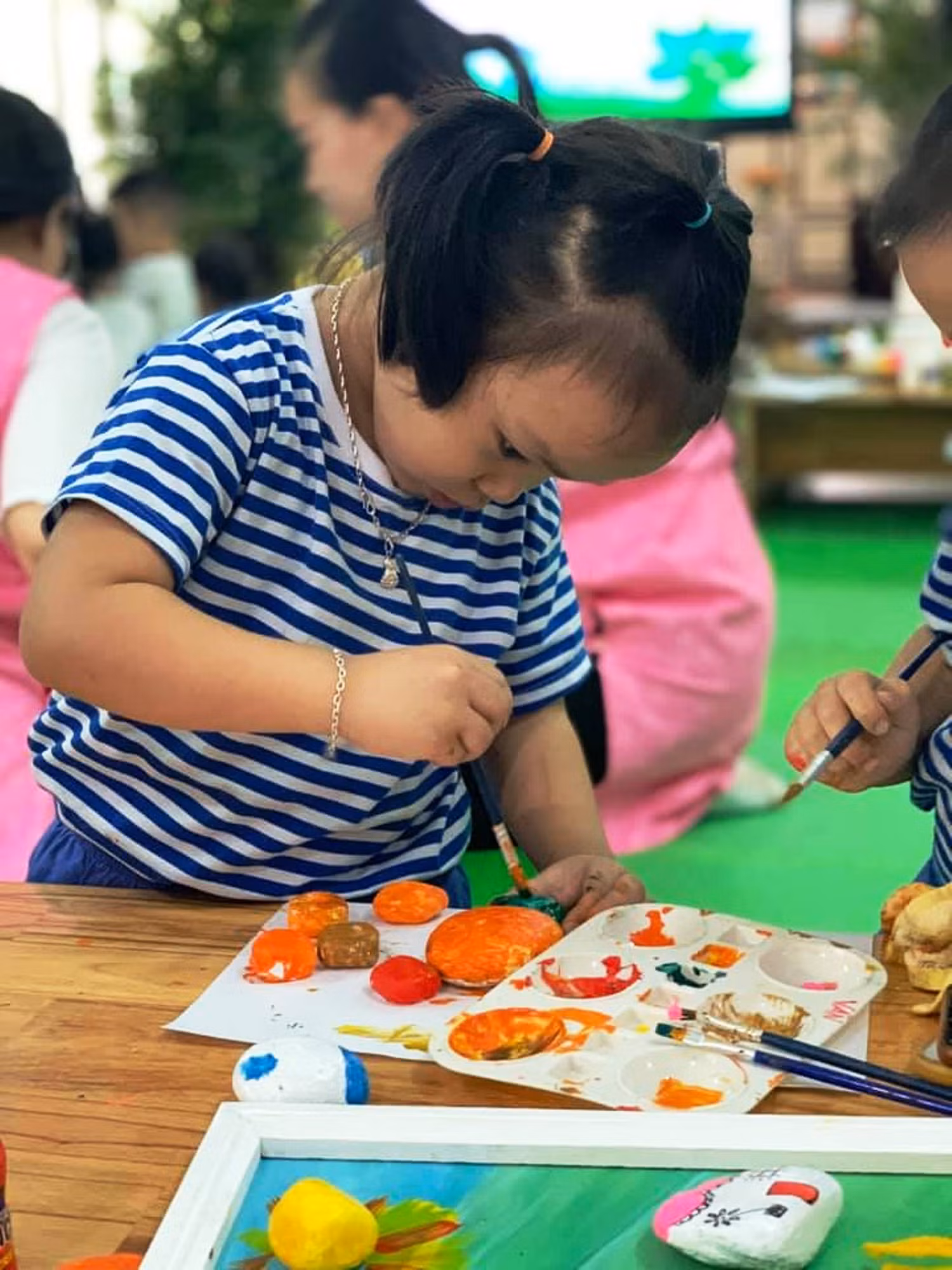 Họa sĩ nhí thể hiện tác phẩm trên đá.
