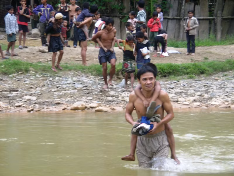 Thầy Phan Văn Khanh (đã công tác 4 năm ở đây) đang cõng học sinh qua suối.