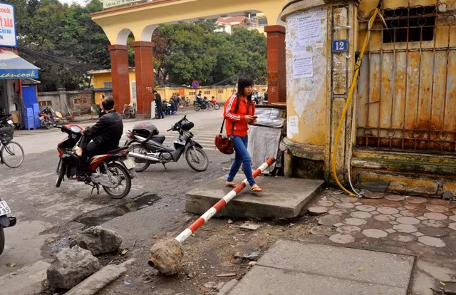 Cột biển chỉ đường đổ và nằm ngang trên vỉa hè. Nhiều người phải bước qua cột chỉ đường này để đi.