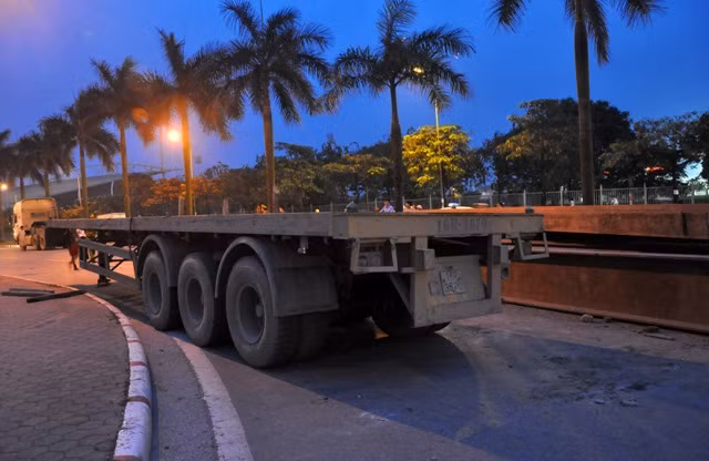 Phần đuôi xe kéo rơ moóc bị lật và đổ nhiều thanh sắt lớn nằm ngang đường.