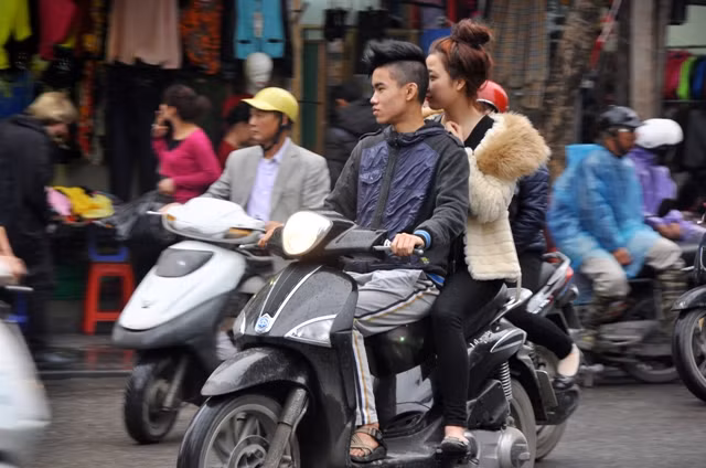 Đôi bạn trẻ thản nhiên ra đường khi không đội mũ bảo hiểm.