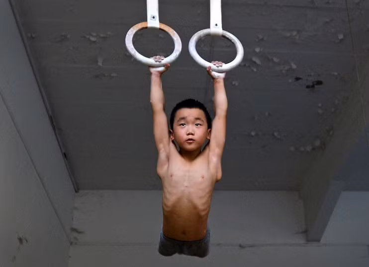Một bé trai được đào tạo để trở thành VĐV Thể dục dụng cụ.