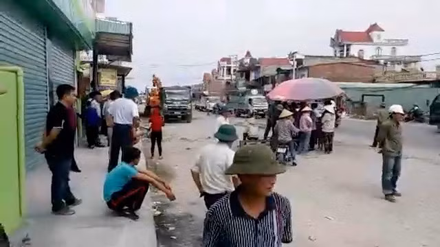 Người dân kê ghế, dựng ô ngay dưới lòng đường yêu cầu nhà thầu phải bồi thường xong mới thi công (ảnh cắt từ clip)